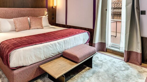 Une chambre moderne avec un grand lit, une table de chevet, une fenêtre avec des rideaux et une vue sur l’extérieur.