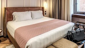 Une chambre d’hôtel avec un grand lit, une table de chevet, une lampe et une fenêtre avec des rideaux.