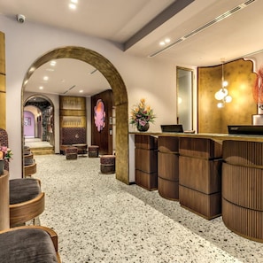A reception area with a modern design, including a reception desk, seating area, and a large mirror. - THE Steps Hotel by Eitch Collection (Rome)