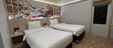 Habitación de hotel con dos camas, un cabecero de madera con obra de arte, una mesita de noche con teléfono y una ventana con vistas.