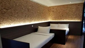 Une pièce avec un mur en bois à texture marquée, un lit avec une literie blanche et une table de chevet.