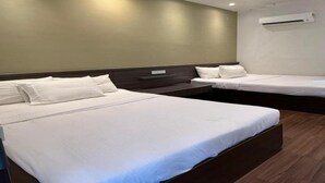 Une chambre d’hôtel avec deux lits, un plancher en bois et un climatiseur fixé au mur.