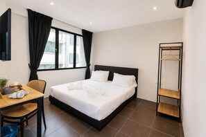 A hotel room with a bed, a desk with a chair, a hanging wardrobe, and a window with curtains. - Swing & Pillows at Damansara Perdana (Petaling Jaya)