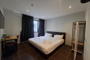 A hotel room with a bed, a desk, a chair, a window with curtains, and a wardrobe. - Swing & Pillows at Damansara Perdana (Petaling Jaya)