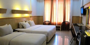 A hotel room with two beds, a desk, a chair, and a television. - Hotel Grand Duta Syariah Palembang (Palembang)