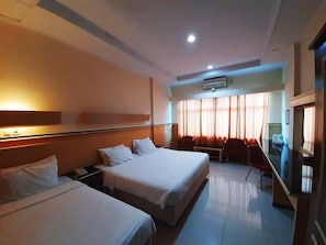 A hotel room with two beds, a desk, and a chair. - Hotel Grand Duta Syariah Palembang (Palembang)