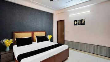 Un dormitorio con cama, mesita de noche, cómoda, una puerta y una pared con tres cuadros enmarcados.