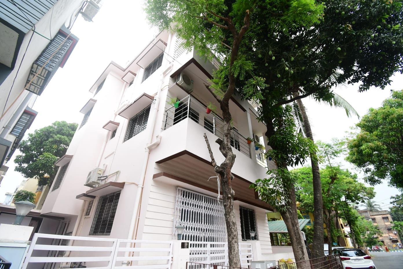 Un edificio residencial de varios pisos con balcones, unidades de aire acondicionado y una entrada protegida por un portón.