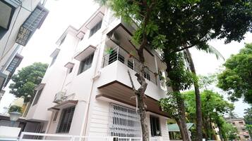 Un edificio residencial de varios pisos con balcones, unidades de aire acondicionado y una entrada protegida por un portón.