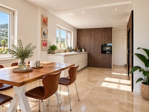 A modern kitchen with a wooden dining table, chairs, and a view of the outdoors. - Stunning 4-Bedroom Villa | Private Pool & Ocean Views | Mijas Costa (Las Lagunas de Mijas)
