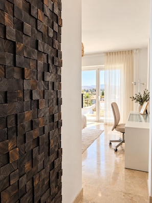 A modern interior with a wooden wall, a glass desk, and a view of a balcony. - Stunning 4-Bedroom Villa | Private Pool & Ocean Views | Mijas Costa (Las Lagunas de Mijas)