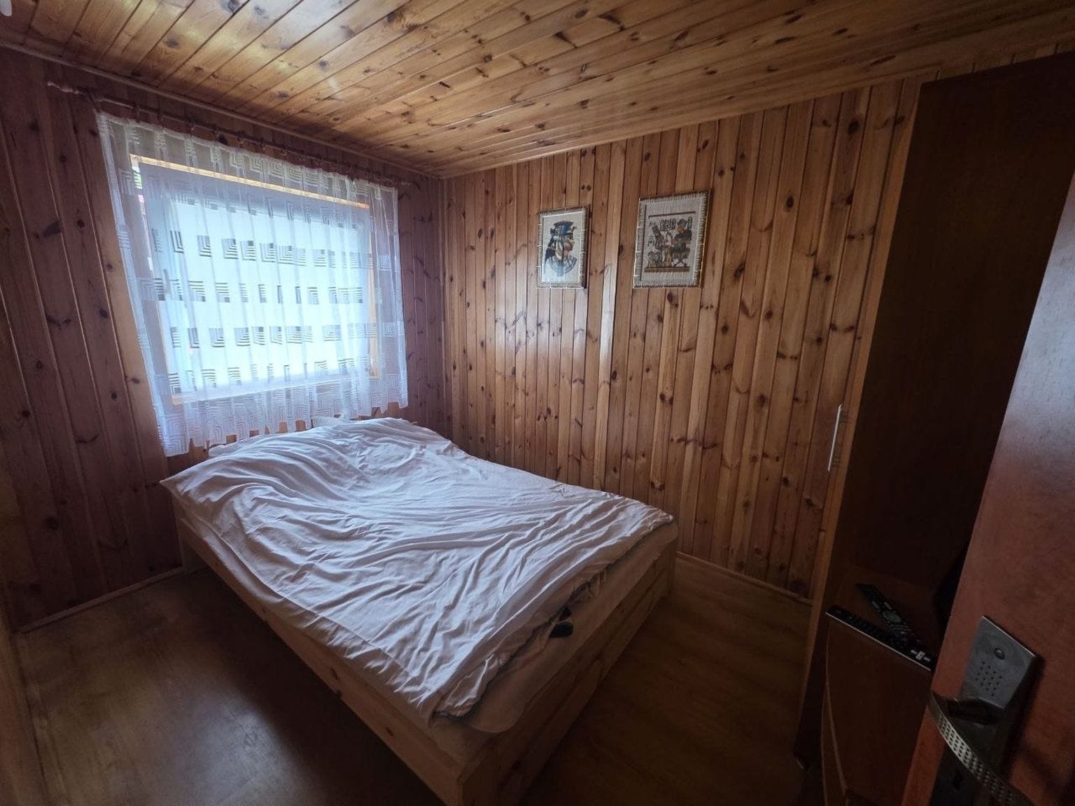 Una habitación con paredes de madera y una cama individual.