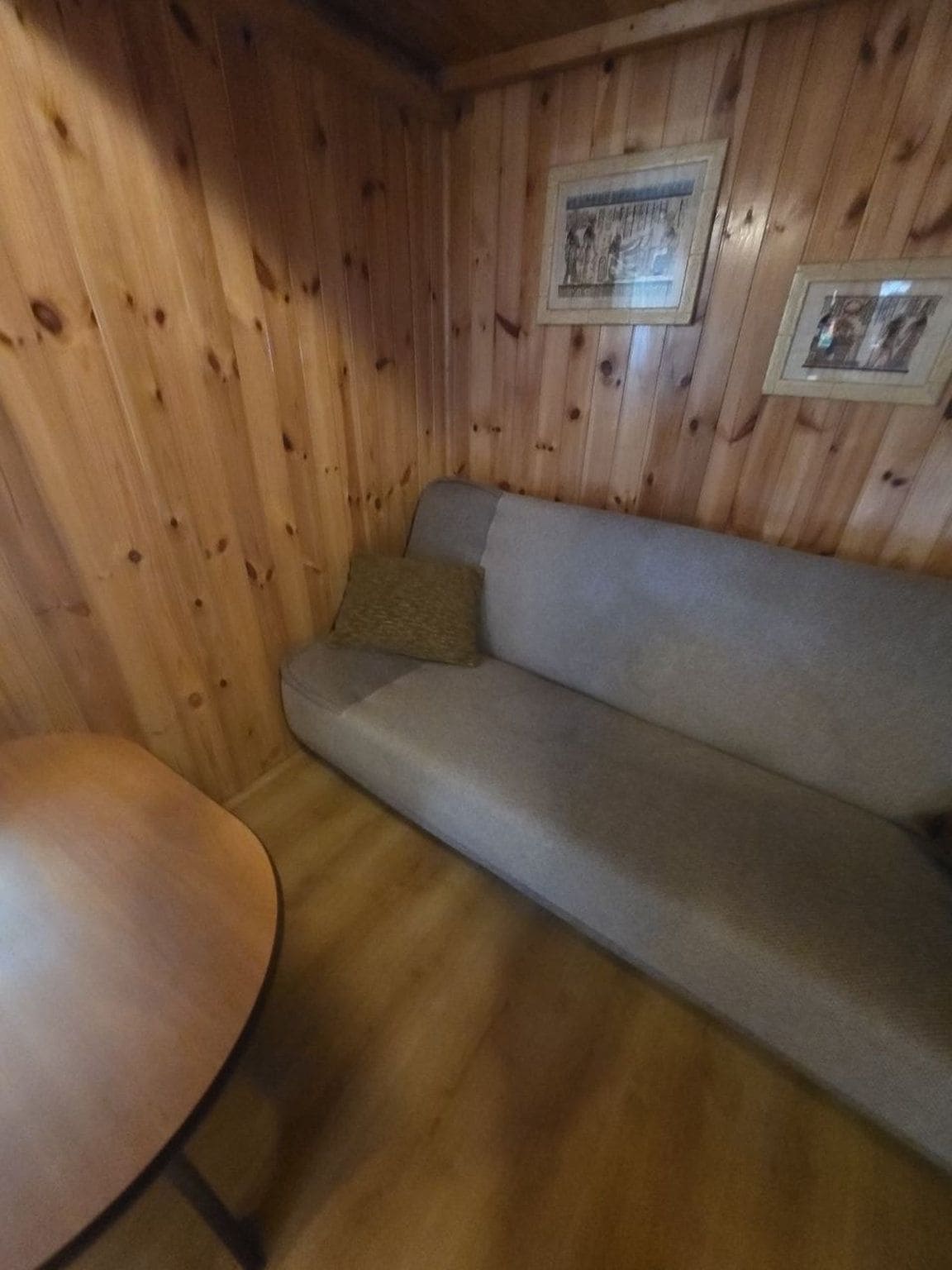 A wooden interior with a sofa and a round table.