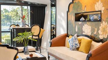 A modern living room with a sofa, a coffee table, and a dining area with chairs and a table.