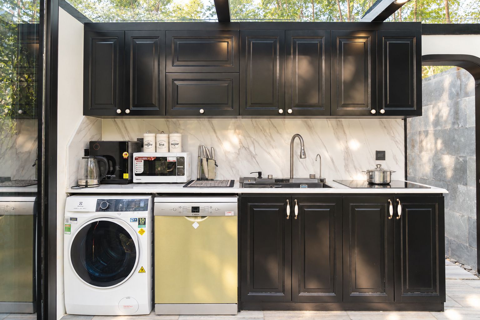A compact kitchen with a washing machine, microwave, and sink.
