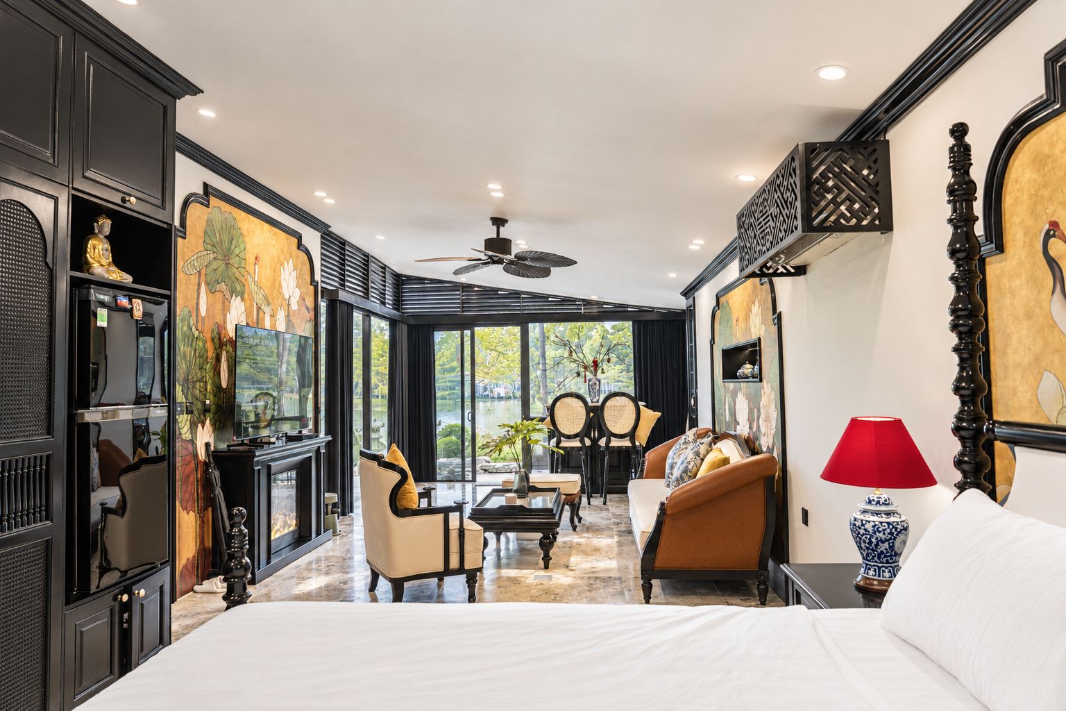 A hotel room with a large bed, a seating area with chairs, a dining table, and artwork on the walls.