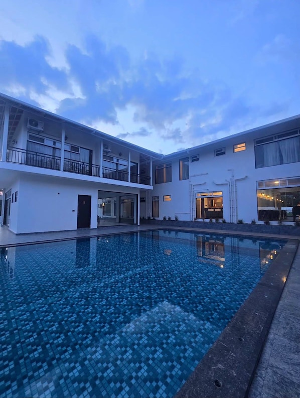 A modern building with a swimming pool, balconies, and large windows.
