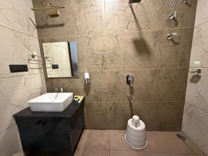 A bathroom with a white sink, black countertop, and a shower with a white container.