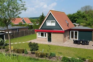 A residential property with a two-story house, a fenced yard, and a patio with outdoor furniture. - Holiday home with 3 bedrooms (Wolphaartsdijk)