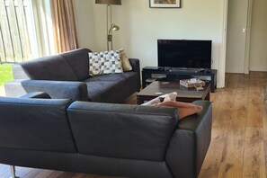A living room with a sofa, a television, and a coffee table. - Holiday home with 3 bedrooms (Wolphaartsdijk)