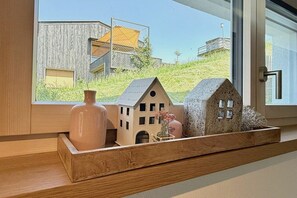Una estantería de madera con casas en miniatura y un florero.