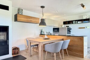 Eine moderne Küche mit einer Holztischinsel, einem Esstisch mit Stühlen und einer hängenden Pendelleuchte.