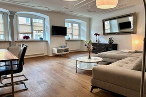 Ein modernes Wohnzimmer mit einer Couch, einem Esstisch mit Stühlen, einem Fernseher und einem Kamin.
