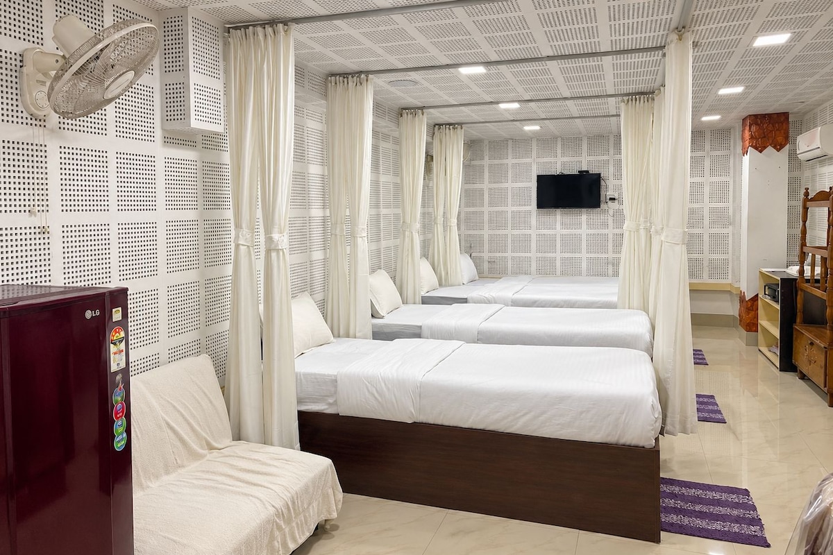 A hotel room with a bed, a TV, a wardrobe, and a ceiling fan.
