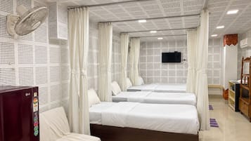 Una habitación de hotel con cama, televisión, armario y ventilador de techo.
