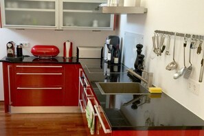 A kitchen with a red cabinet, a coffee maker, and utensils hanging on the wall. - Holiday apartment with 1 bedroom (Nonnenhorn)