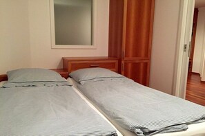 A bedroom with two single beds, a wooden wardrobe, and a mirror on the wall. - Holiday apartment with 1 bedroom (Nonnenhorn)