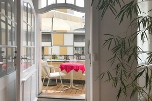 An open door leading to a balcony with a table and chairs, a hanging umbrella, and a plant. - Holiday apartment with 1 bedroom (Lindau)