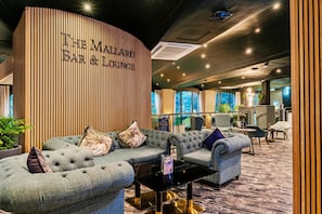 Un espace détente doté d’un mur en bois aux lignes courbes, de sièges confortables et d’une vue sur l’extérieur.
