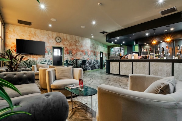 Un hall d’hôtel avec des sièges, un bar et un téléviseur.