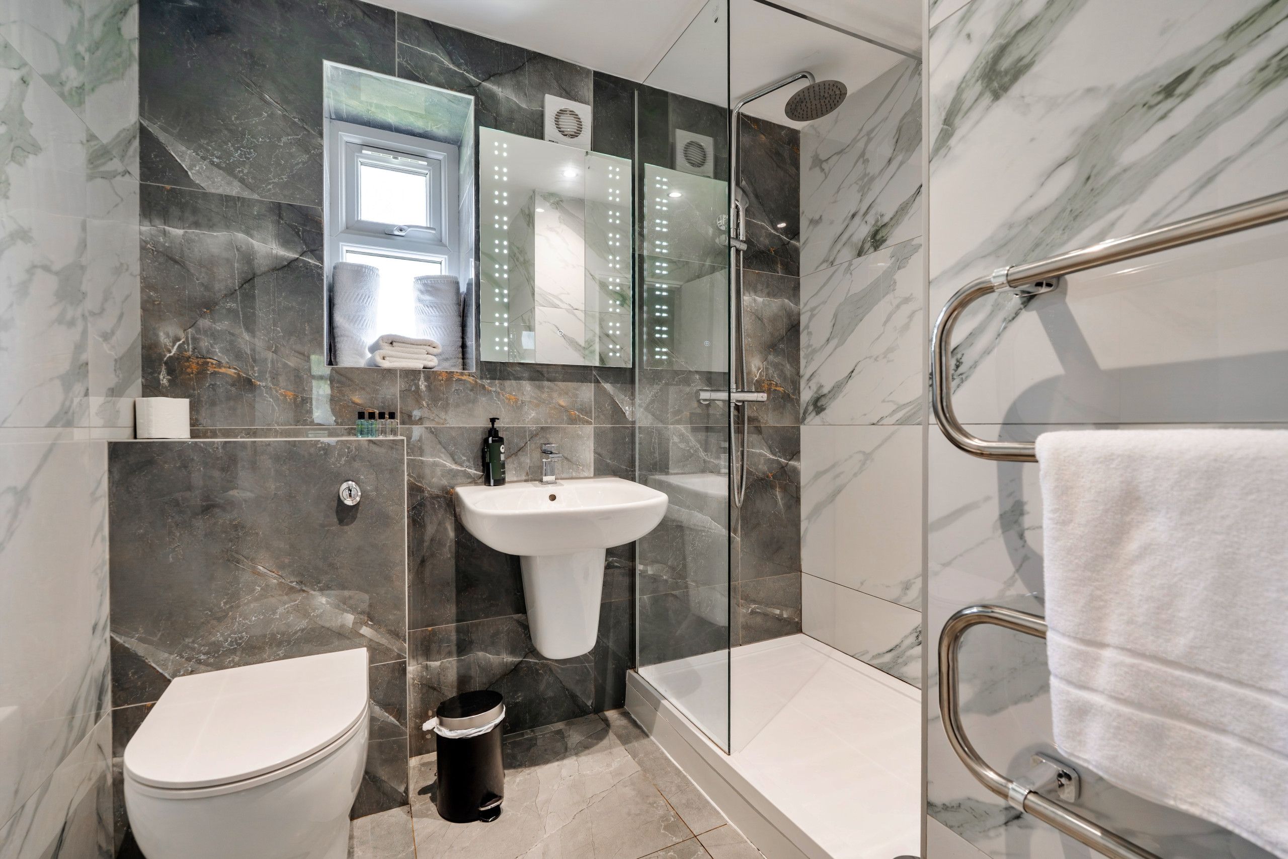 Une salle de bain moderne équipée de toilettes, d’un lavabo et d’un espace douche.