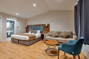 Une chambre d’hôtel moderne, équipée d’un lit, d’un canapé, d’un fauteuil et d’une petite table ronde.