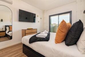 Ein modernes Schlafzimmer mit Bett, Wandfernseher, Schminktisch und Fenster mit Blick.