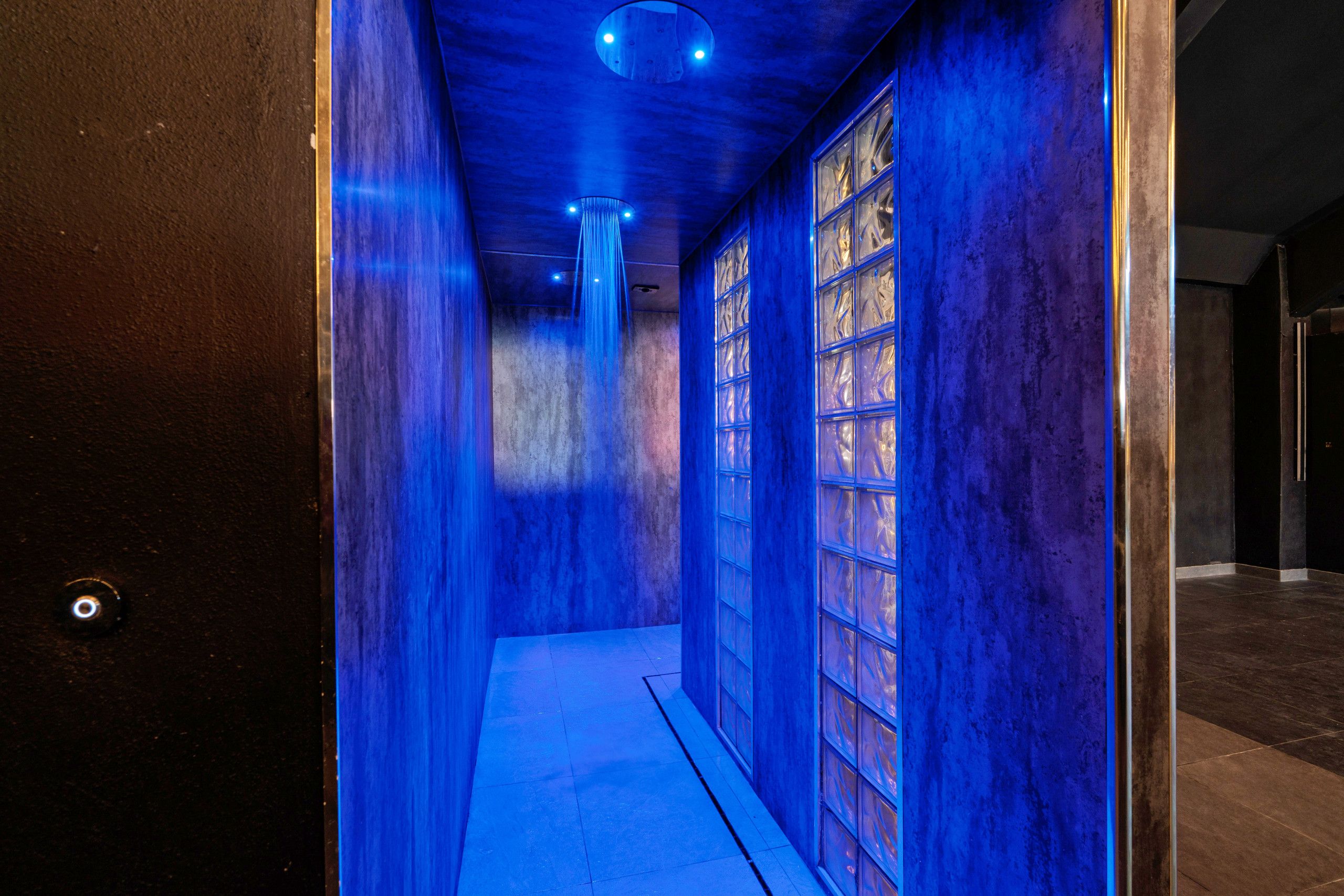 Un couloir avec un mur éclairé en bleu et une série de fenêtres.