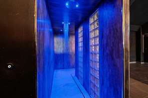 A hallway with a blue-lit wall and a series of windows.