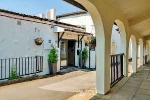 A covered walkway with white walls and black railings, leading to a building entrance with a sign for a leisure club and spa.