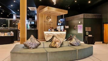 Un moderno vestíbulo de hotel con mostrador de recepción, zona de estar y un amplio ventanal.
