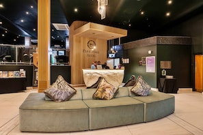 A modern hotel lobby with a reception desk, seating area, and a large window. - Park Hall, 2 Bedroom Apartment (Charnock Richard)
