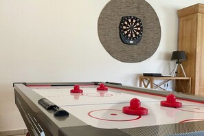A foosball table with red and black players, a dartboard, and a lamp. - Holiday home with 4 bedrooms (Blekendorf)