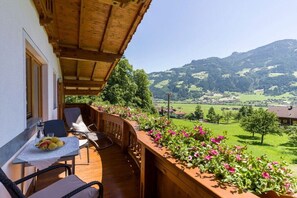 A balcony with a table set for two, overlooking a mountainous landscape. - Holiday apartment with 1 bedroom (Schwendau)