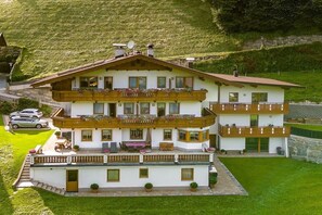 A multi-story chalet with balconies, a covered terrace, and a stone wall. - Holiday apartment with 1 bedroom (Schwendau)