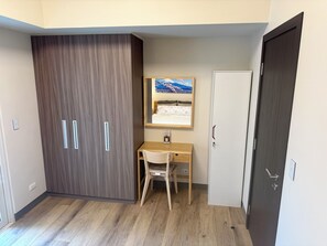 A room with a wardrobe, a desk with a chair, a bed, and a door. - Park McKinley West Tower-A Japanese Inspired Cozy Quiet 1BR Condo 85"HDTV 穏やかな (Taguig)