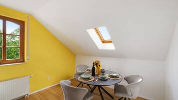 Un comedor con una mesa dispuesta para cuatro personas, un tragaluz y una ventana con vistas a la vegetación.
