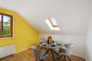 A dining area with a table set for four, a skylight, and a window with a view of greenery.