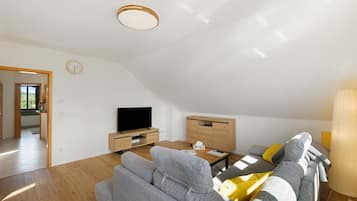 Uma sala de estar moderna com televisão de tela plana, um sofá, uma mesa de centro e um armário de madeira.