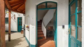 A traditional building with a wooden staircase leading to an upper level, a green door, and a white wall with a textured finish.